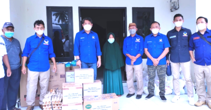 Ketua DPW Nasdem Gorontalo, Hamim Pou didampingi Ketua DPD Nasdem Pohuwato, Iwan S. Adam tampak menyerahkan paket sembako kepada salah satu warga korban banjir Dengilo-Paguat. (Foto : Istimewa)